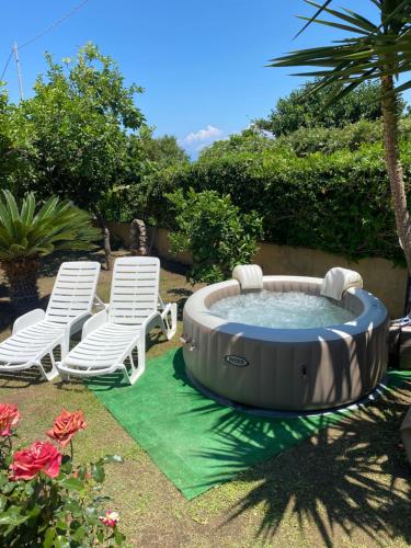 a hot tub in a yard with two lawn chairs at Villa Saturno in Tropea