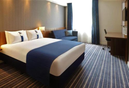 Holiday Inn Express Poole, an IHG Hotel في بول: غرفة الفندق بسرير كبير ومكتب