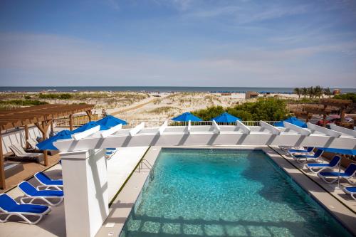 een zwembad met stoelen en blauwe parasols bij Mahalo Diamond Beach Resort in Wildwood Crest