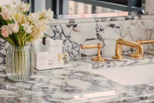 - un comptoir de salle de bains avec un vase de fleurs et un lavabo dans l'établissement Hotel Barrière Fouquet's New York, à New York