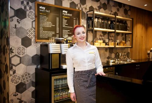 a woman standing in front of a counter in a restaurant at Staycity Aparthotels Birmingham Jewellery Quarter in Birmingham