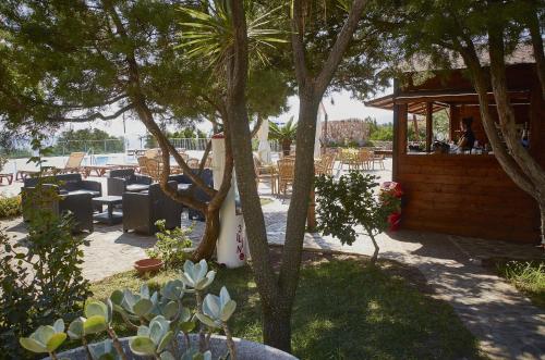 een patio met tafels, stoelen en bomen bij Parco Blu in Cala Gonone