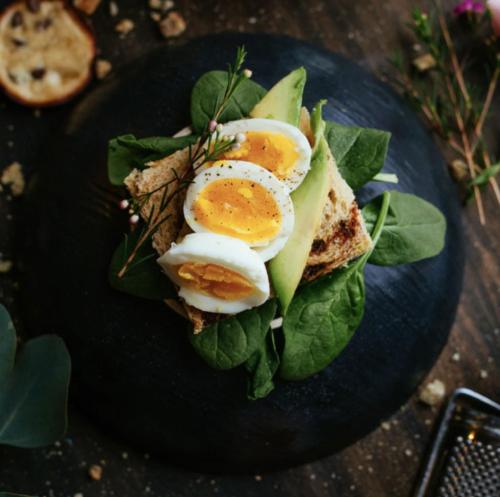 a plate of food with eggs and greens on it at EXchange Hotel Vancouver in Vancouver