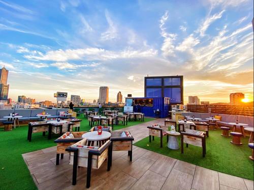 eine Dachterrasse mit Tischen und Stühlen auf einem Gebäude in der Unterkunft Hotel Indigo Kaohsiung Central Park, an IHG Hotel in Kaohsiung