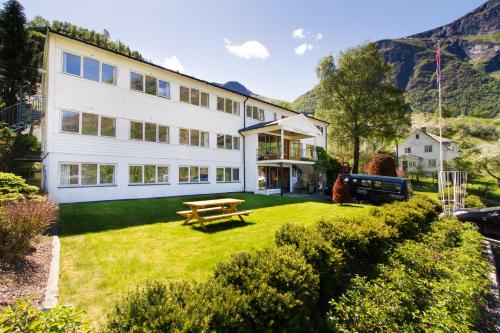 - un grand bâtiment blanc avec une table de pique-nique dans la cour dans l'établissement Heimly Pensjonat, à Flåm