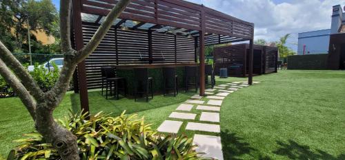 um jardim com uma mesa e cadeiras sob uma pérgola em Fort Lauderdale Grand Hotel em Fort Lauderdale