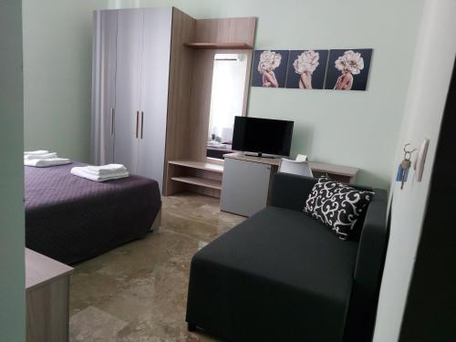 a bedroom with a bed and a couch and a television at Arte Mia B&B in Reggio di Calabria