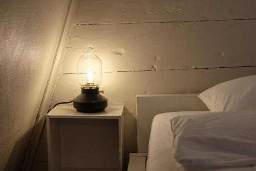 a lamp on a night stand next to a bed at Charming Bergen house, rare historic house from 1779, Whole house in Bergen