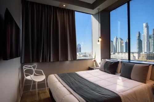 a bedroom with a large window with a bed and a chair at Believe Madero Hotel in Buenos Aires