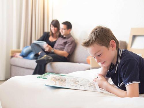 Un jeune garçon qui se couche sur une table en lisant un livre dans l'établissement Novotel Wolverhampton City Centre, à Wolverhampton