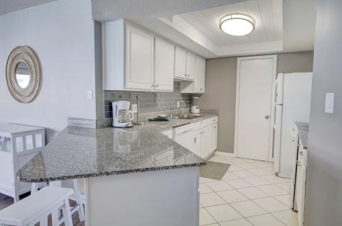 a kitchen with white cabinets and a granite counter top at El Matador 454 - Beautiful views of the Gulf and pool - Includes seasonal beach service! in Fort Walton Beach