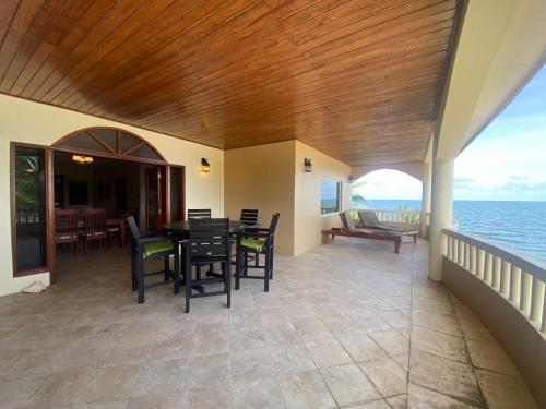 a porch with a table and chairs and the ocean at Los Porticos in Placencia Village