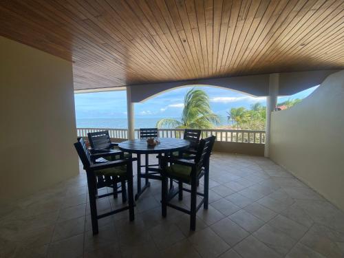 a dining room with a table and chairs on a balcony at Los Porticos in Placencia Village