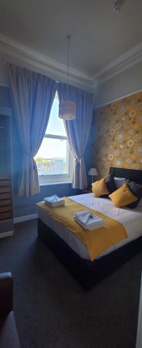 a bedroom with a large bed with blue curtains at Alexandra Hotel in Eastbourne