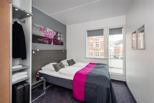 ein Schlafzimmer mit einem Bett mit einer rosa Decke darauf in der Unterkunft Cabinn City in Kopenhagen