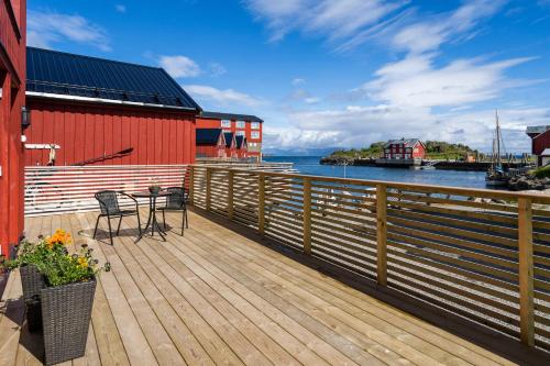 une terrasse en bois avec une table et des chaises sur l'eau dans l'établissement Finnvika Lodges, à Stamsund