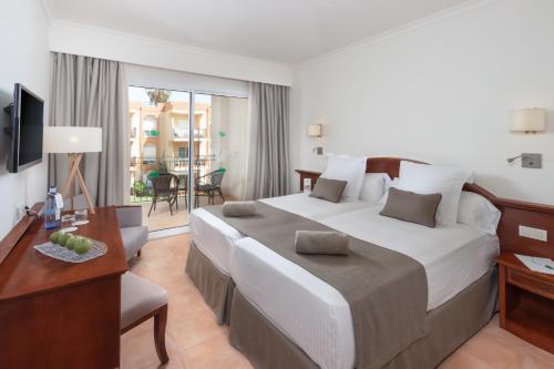 a hotel room with a large bed and a desk at Valentin Sancti Petri in Chiclana de la Frontera