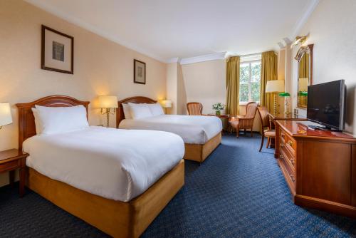 um quarto de hotel com duas camas e uma televisão de ecrã plano em Killarney Plaza Hotel & Spa em Killarney