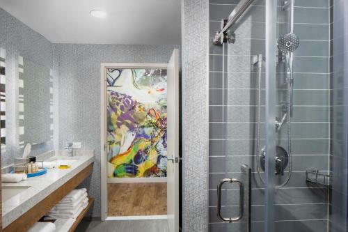 a bathroom with a shower and a painting on the wall at Hotel Indigo Gainesville-Celebration Pointe, an IHG Hotel in Gainesville