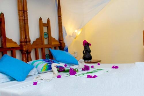 een bed met paarse bloemen erop bij Tembo Beach Cottage in Malindi