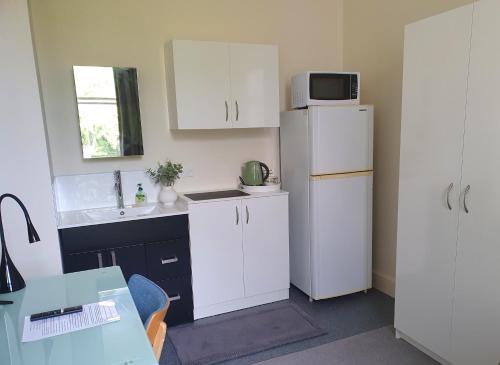 a small kitchen with a white refrigerator and a sink at Travel Stay City Hostel in Dunedin