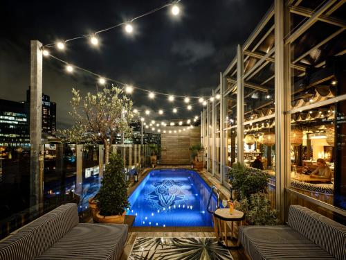 a rooftop patio with a swimming pool at night at Virgin Hotels London - Shoreditch in London