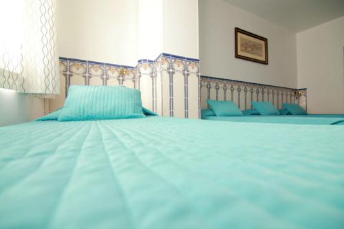 a large bed with blue sheets and a window at Residencial Joao XXI in Lisbon