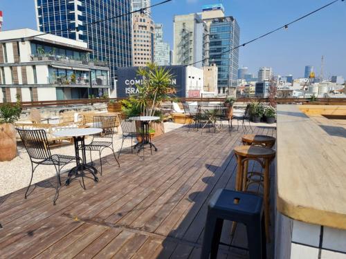 a wooden deck with tables and chairs on a rooftop at Rena's House in Tel Aviv