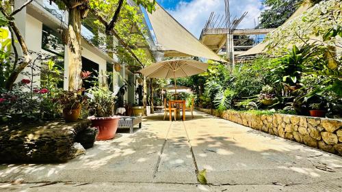 eine Terrasse mit einem Sonnenschirm, Stühlen und Pflanzen in der Unterkunft Hidden of Cailan Inn in El Nido