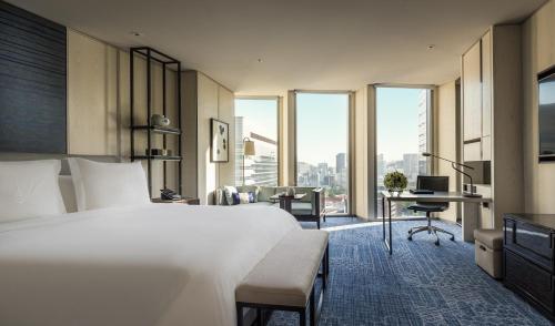 um quarto de hotel com uma cama, uma secretária e janelas em Four Seasons Hotel Seoul em Seul