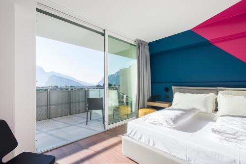 een slaapkamer met een groot bed en een balkon bij HOODY ACTIVE & HAPPINESS HOTEL in Arco