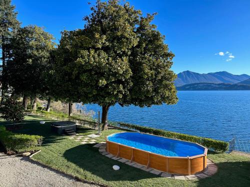 a swimming pool in the grass next to a lake at Relais Casali della Cisterna in Belgirate