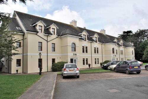 duży budynek z samochodami zaparkowanymi przed nim w obiekcie The Elms Apartments Ramsey Isle of Man UK w mieście Ramsey