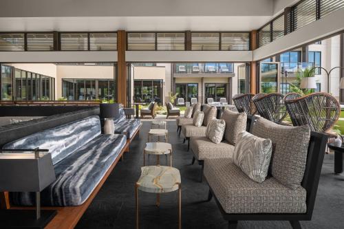 a lobby with couches and tables and windows at AC Hotel by Marriott Maui Wailea in Wailea