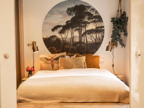 a bedroom with a large bed with a painting on the wall at Stayatsas Tiny House Julia in de bossen op de Veluwe! in Epe