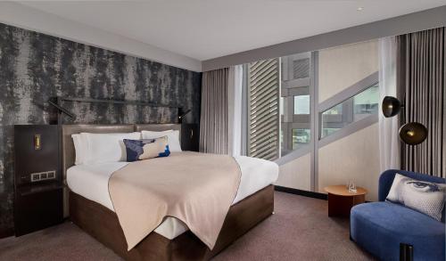 a bedroom with a large bed and a blue chair at Montcalm East, Autograph Collection in London