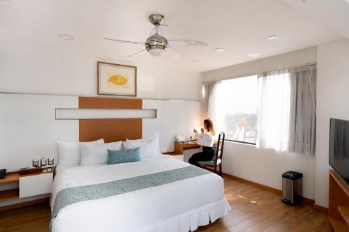 a woman sitting at a desk in a hotel room at Suites Coben Apartamentos Amueblados in Mexico City