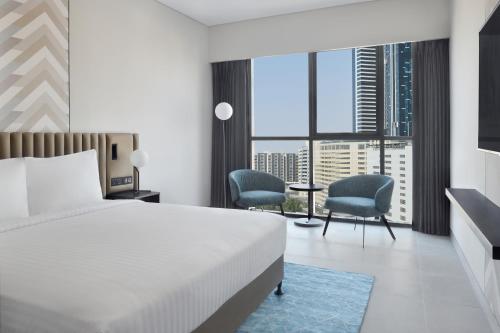 ドバイにあるCourtyard by Marriott World Trade Centre, Dubaiのベッド1台と椅子2脚が備わるホテルルームです。