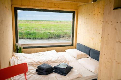 Cama en habitación pequeña con ventana en Tiny House Nature 14 Zur Meerseite - Green Tiny Village Harlesiel, en Carolinensiel