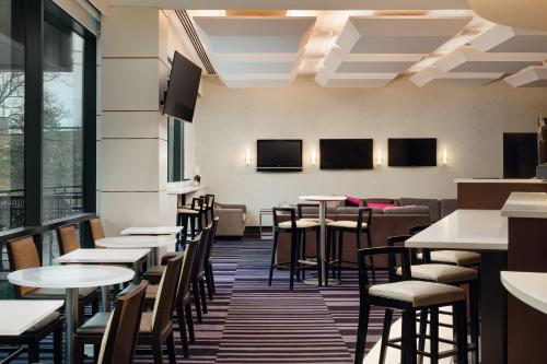 un comedor con mesas, sillas y ventanas en Courtyard by Marriott New York JFK Airport, en Queens