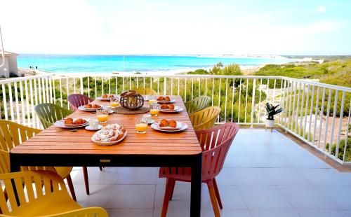 un tavolo in legno su un balcone con vista sull'oceano di Apartments Es Trenc a Ses Covetes