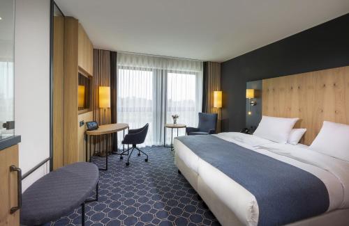 a hotel room with a large bed and a desk at Maritim Hotel Ingolstadt in Ingolstadt