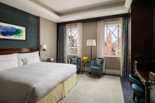 a hotel room with a bed and a chair and windows at The Beaumont Mayfair in London