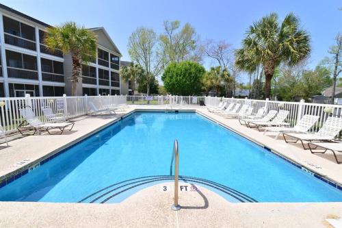 uma piscina com espreguiçadeiras e um edifício em All New Luxury Beach Retreat 1 Mile to Beach w Pool em Myrtle Beach