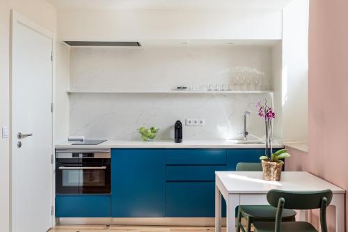 a kitchen with blue cabinets and a table with chairs at JOIVY Flats next to Rossio Square and main Lisbon attractions in Lisbon