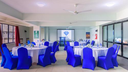 a conference room with tables and blue chairs and a screen at Hotel Sapphire in Mombasa