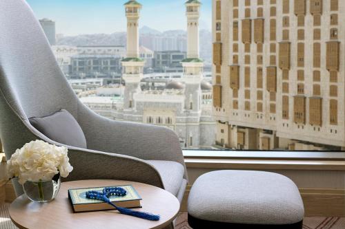 um quarto com uma cadeira, uma mesa e uma janela em Jumeirah Jabal Omar Makkah em Meca