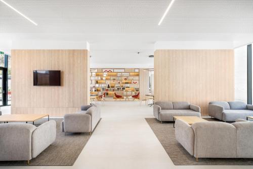 a lobby with couches and a tv on a wall at Moov Hotel Lisboa Oriente in Lisbon