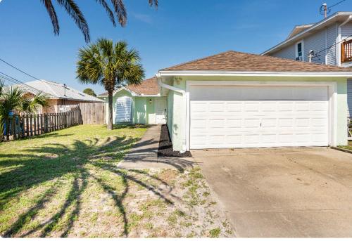 a house with a white garage and a palm tree at Beautiful House Sleeps 12 - Hot Tub - Breakfast - Walk to Beach in Panama City Beach