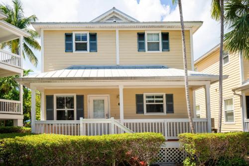 una casa gialla con portico e cespugli di Coral Hammock Poolside Home a Key West